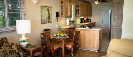 A kitchen with wooden cabinets, a dining table with chairs, a refrigerator, and a coffee maker.