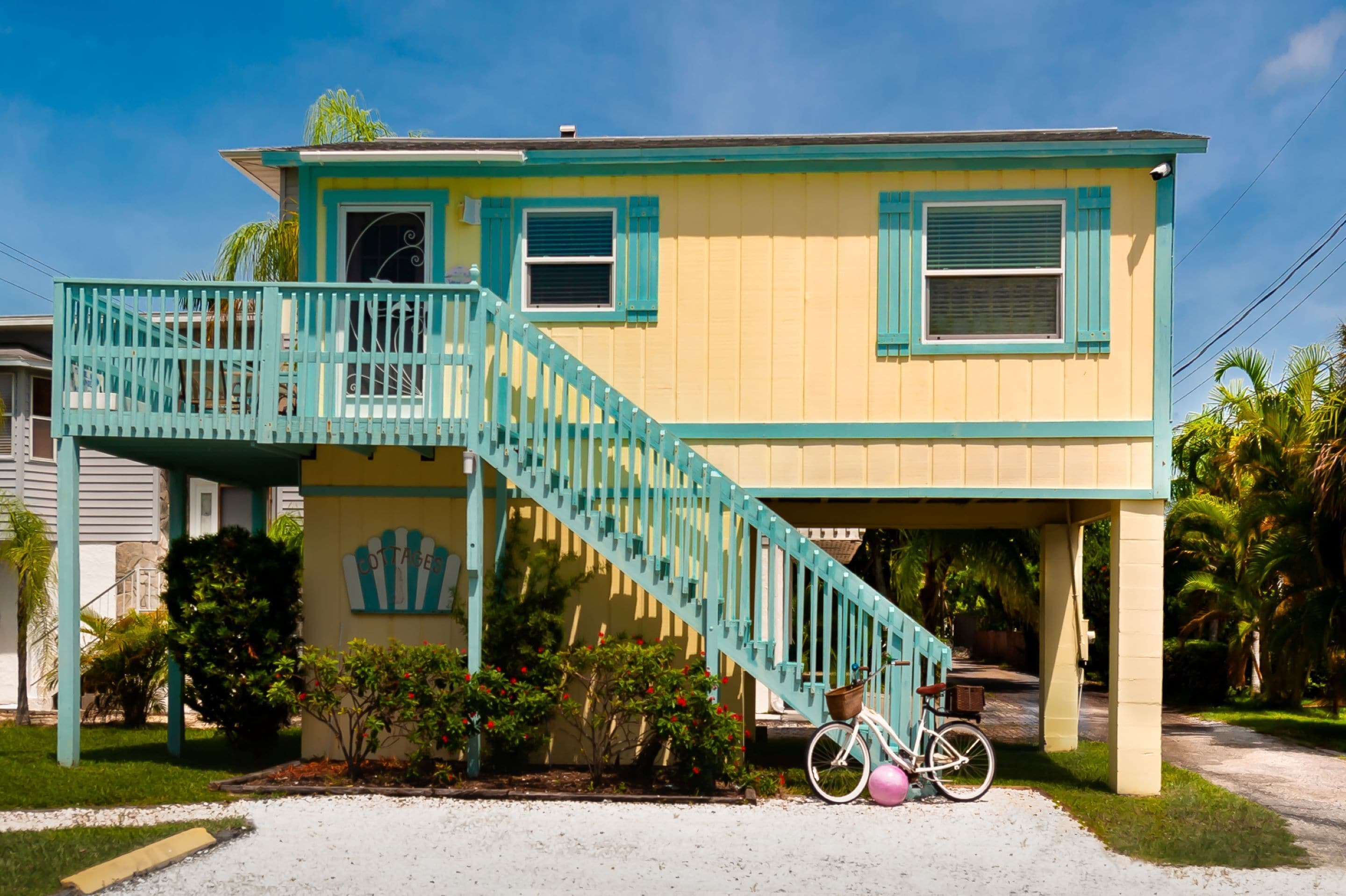 A two-story house with a turquoise staircase and a bicycle parked in front.