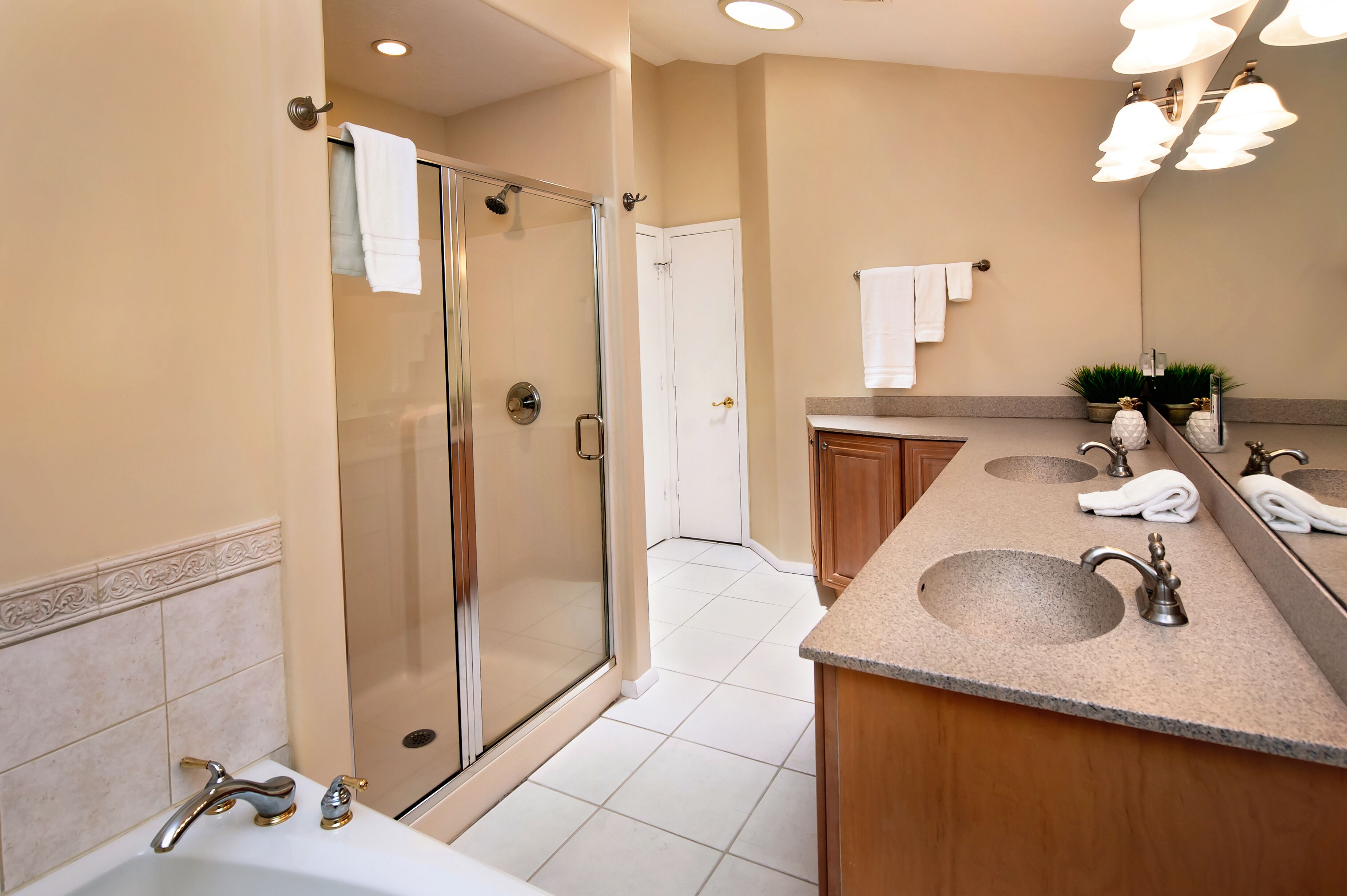 Un baño moderno con cabina de ducha de vidrio, tocador con dos lavamanos y un espejo grande.