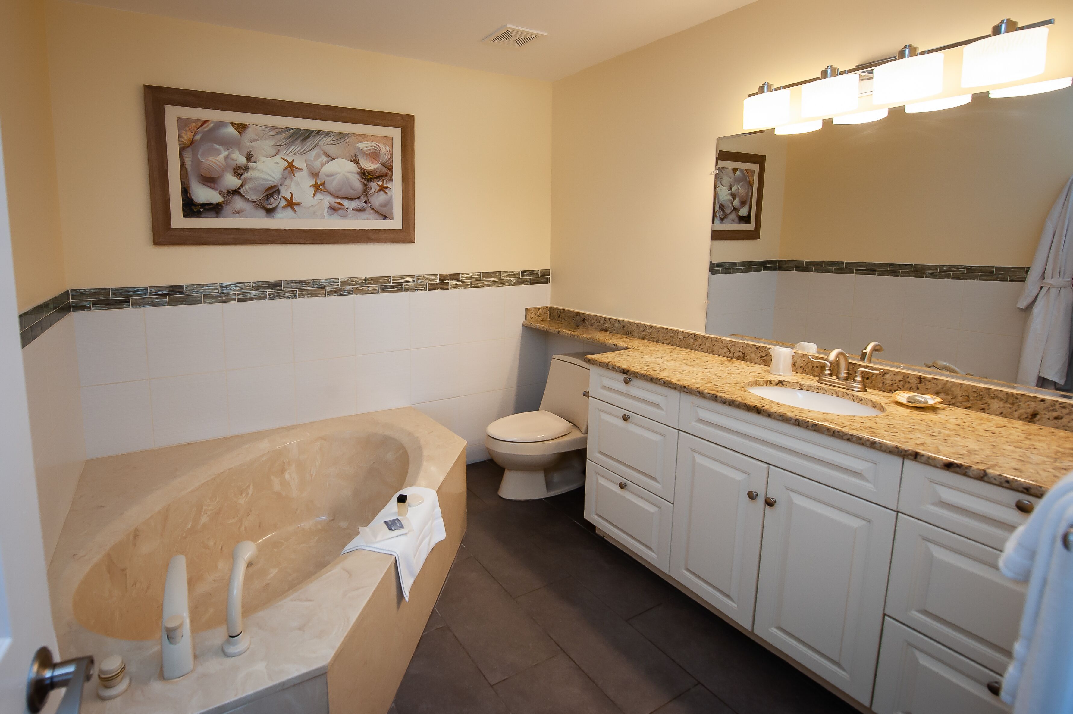 A bathroom with a bathtub, toilet, sink, and vanity.