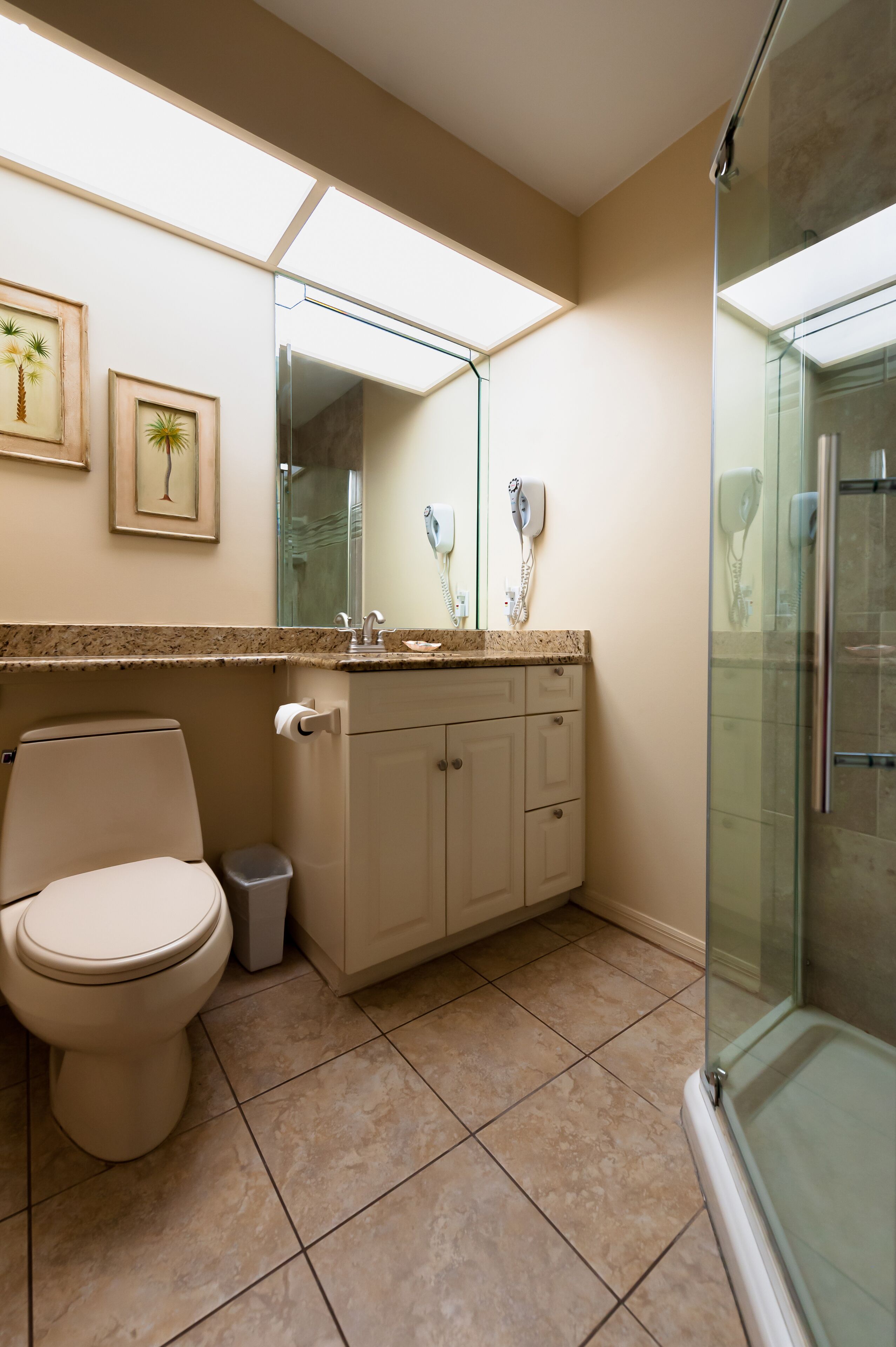 A modern bathroom with a toilet, vanity, and glass shower enclosure.