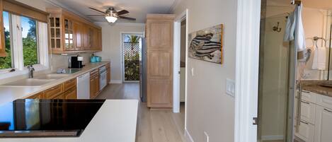 Une cuisine moderne avec des meubles en bois, une cuisinière noire et une cabine de douche en verre.