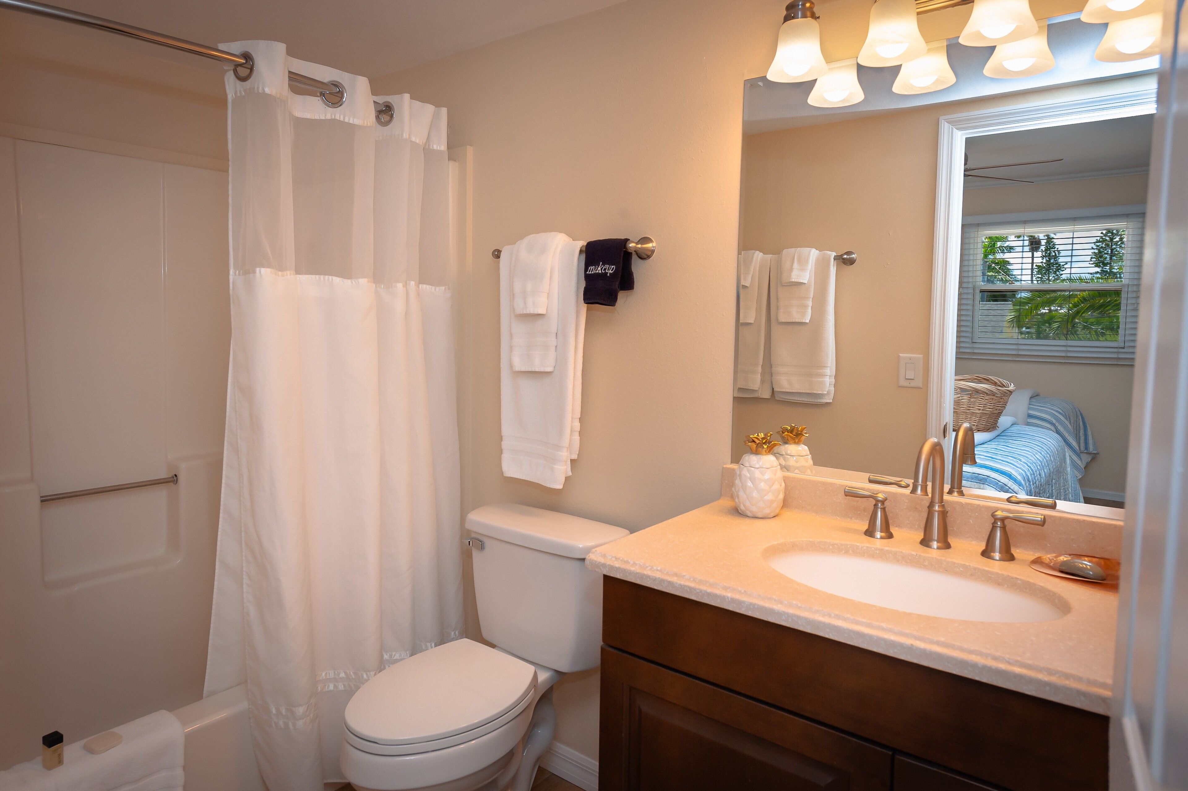 A bathroom with a toilet, a sink, a mirror, and a shower curtain.