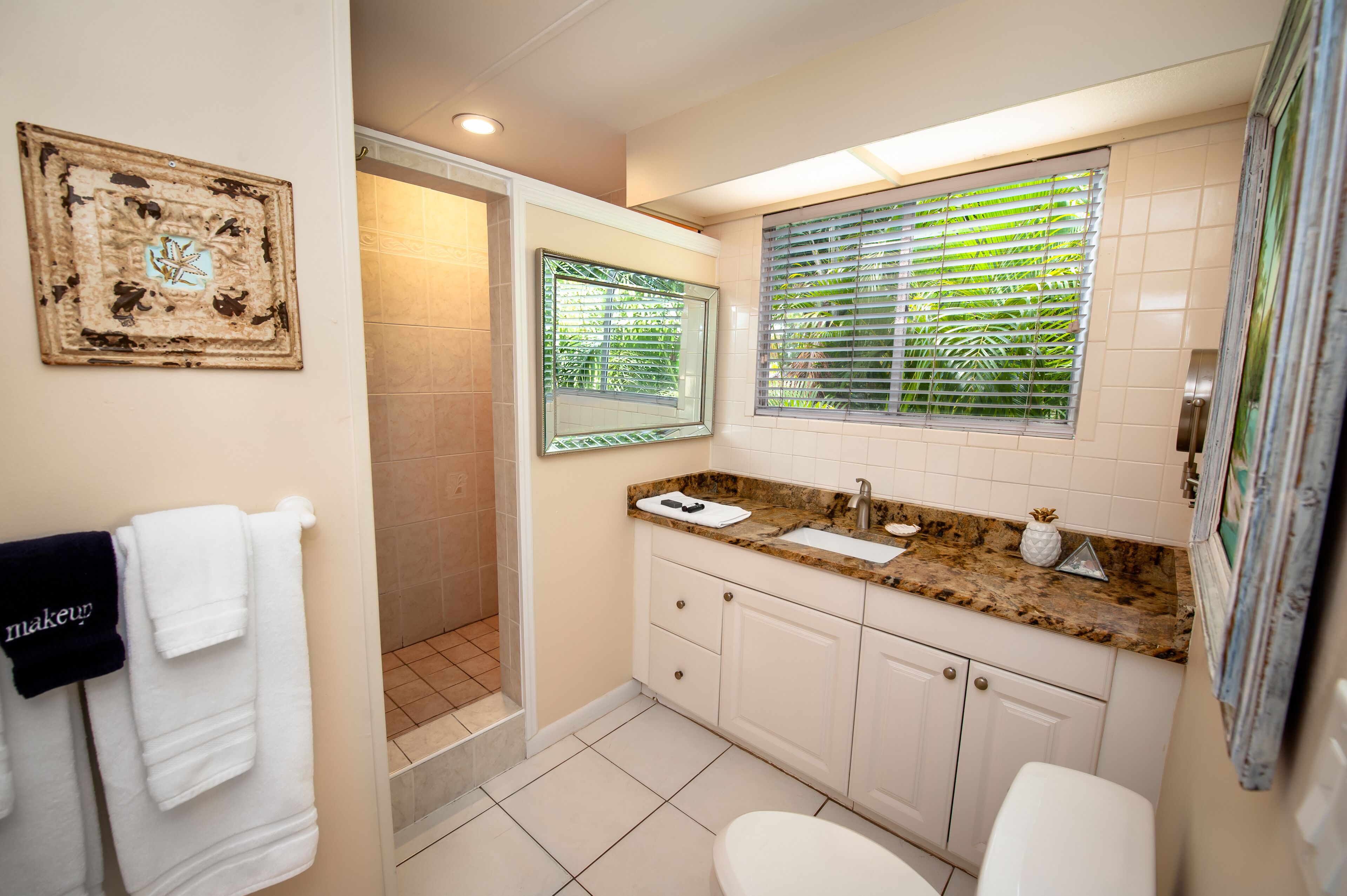A bathroom with a shower, toilet, sink, and a towel rack with towels.