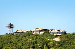 A hillside property with three houses, each with a distinct structure and surrounded by lush greenery.