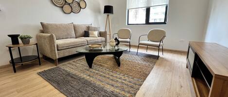 Uma sala de estar com sofá, duas poltronas, mesa de centro, tapete e decoração nas paredes.