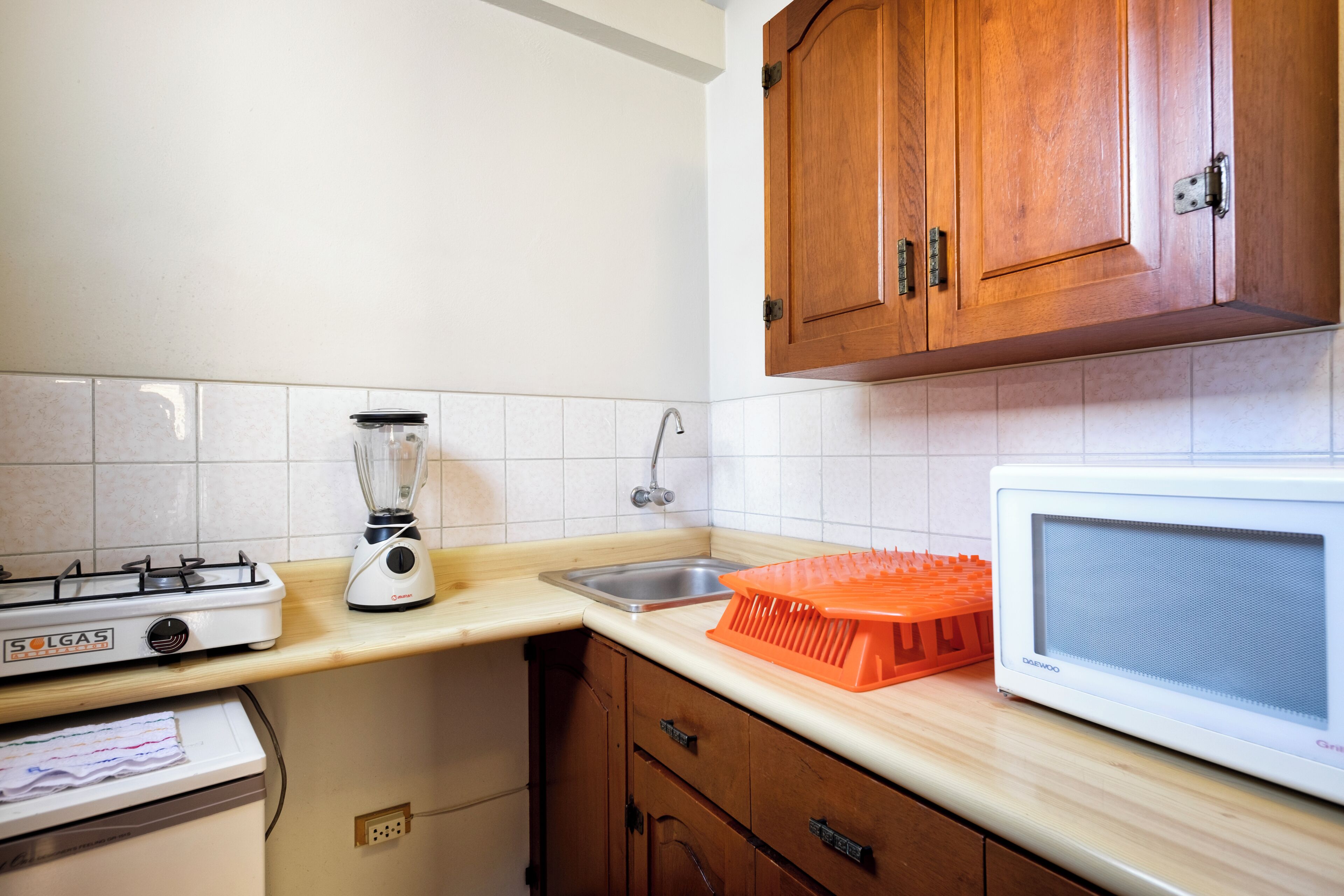 A kitchen with a gas stove, a blender, a microwave, and wooden cabinets.