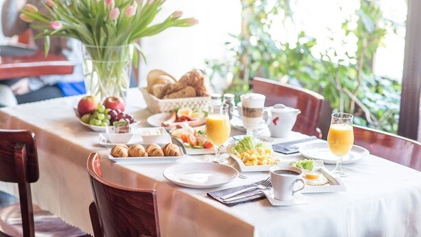A breakfast table set with croissants, fruits, eggs, and juice. - City Center Rooms (Lodz)