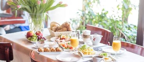 Una mesa de desayuno servida con cruasanes, frutas, huevos y jugo.