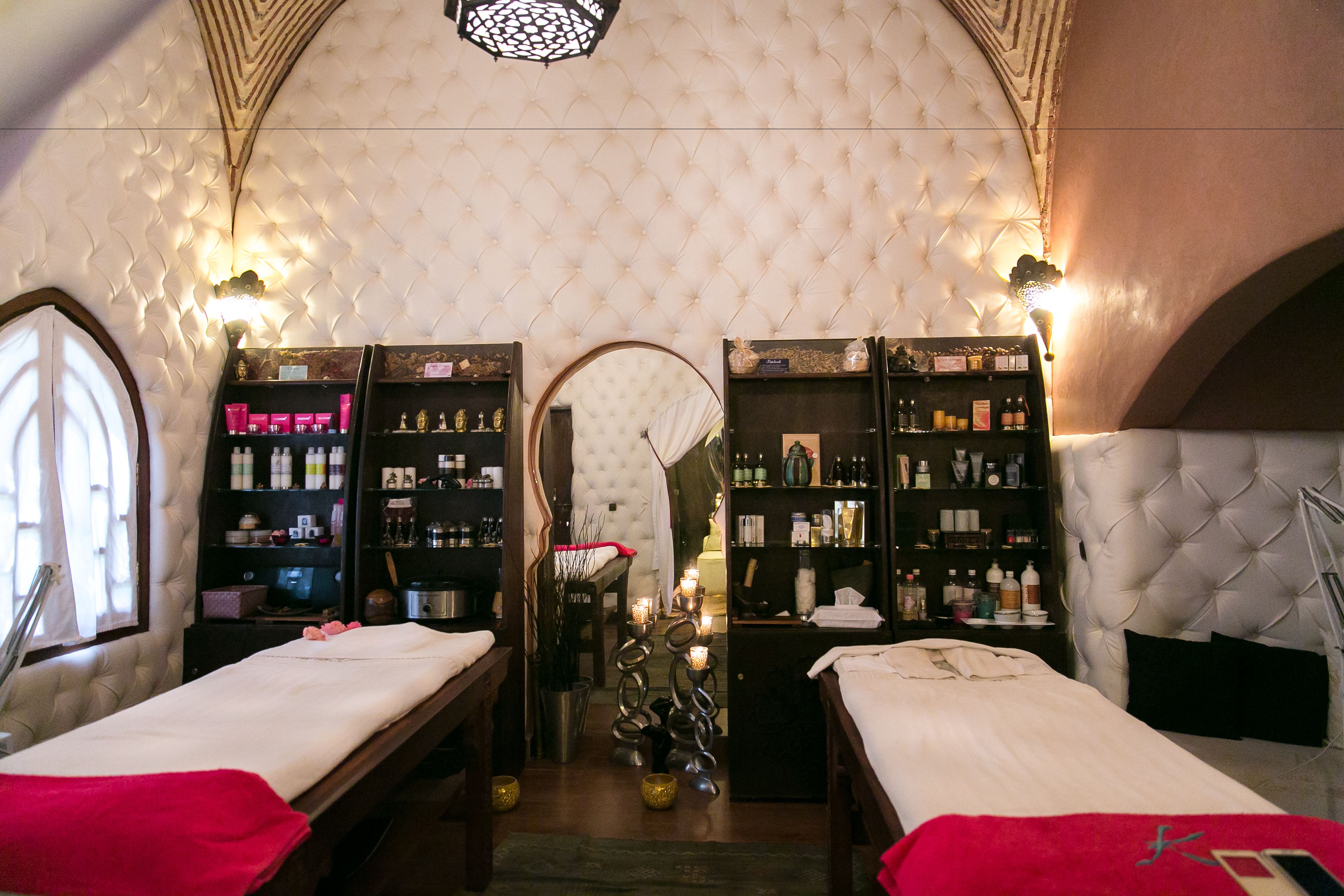 Un cuarto de spa con dos camas, un espejo y repisas con artículos de aseo.