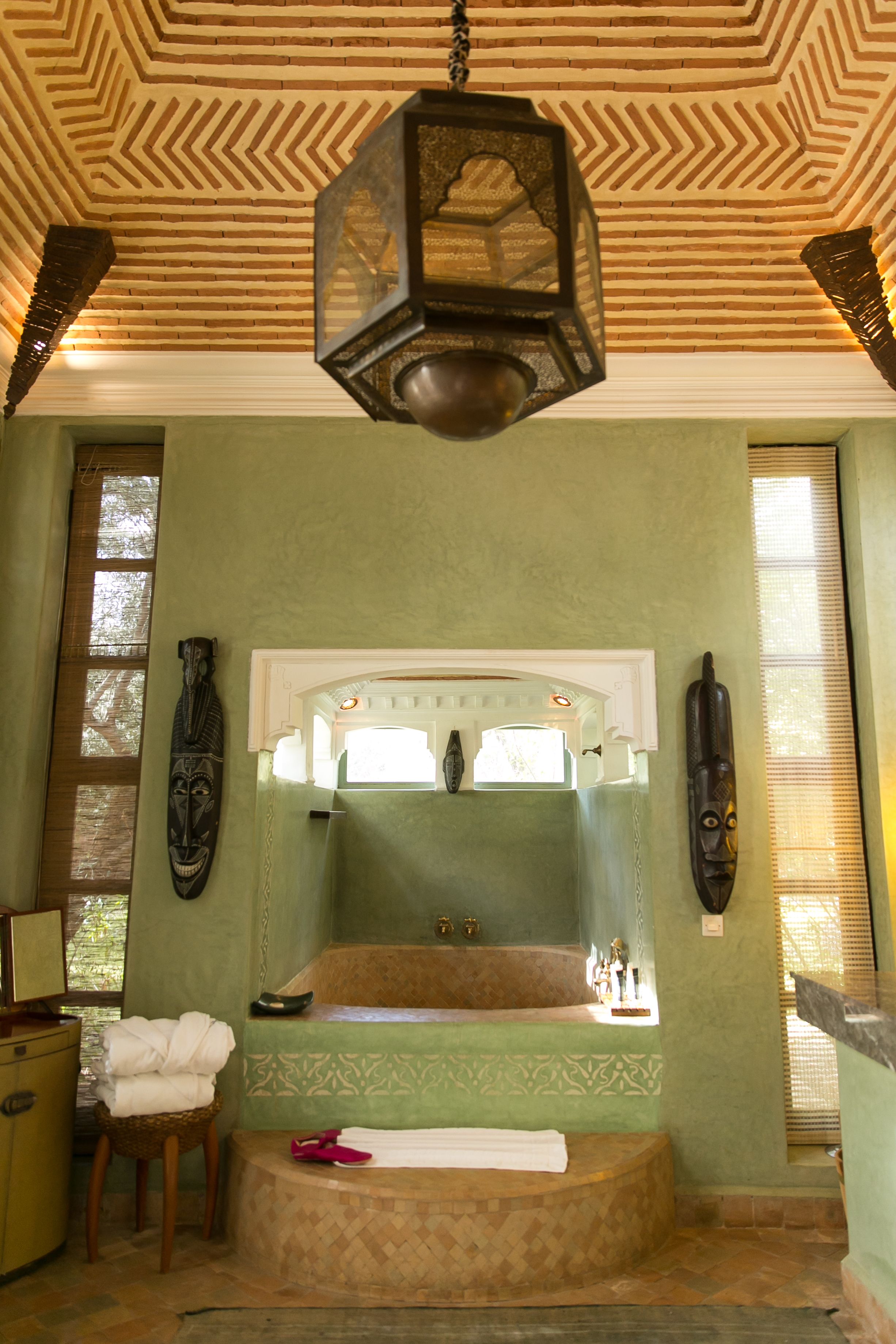 A bathroom with a large mirror, a bathtub, and a hanging light fixture.