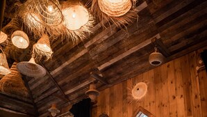 A rustic interior with wooden walls, a woven ceiling, and a large arched doorway leading outside. - Lodge K Hôtel & Spa (Marrakech)