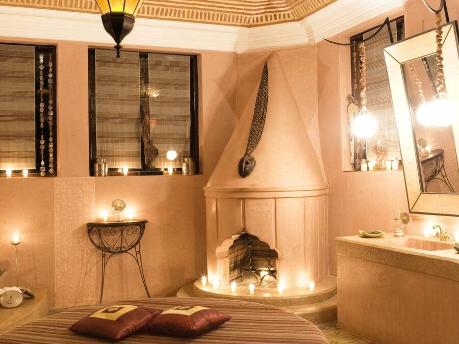 A room with a round bed, a fireplace, and a large mirror.
