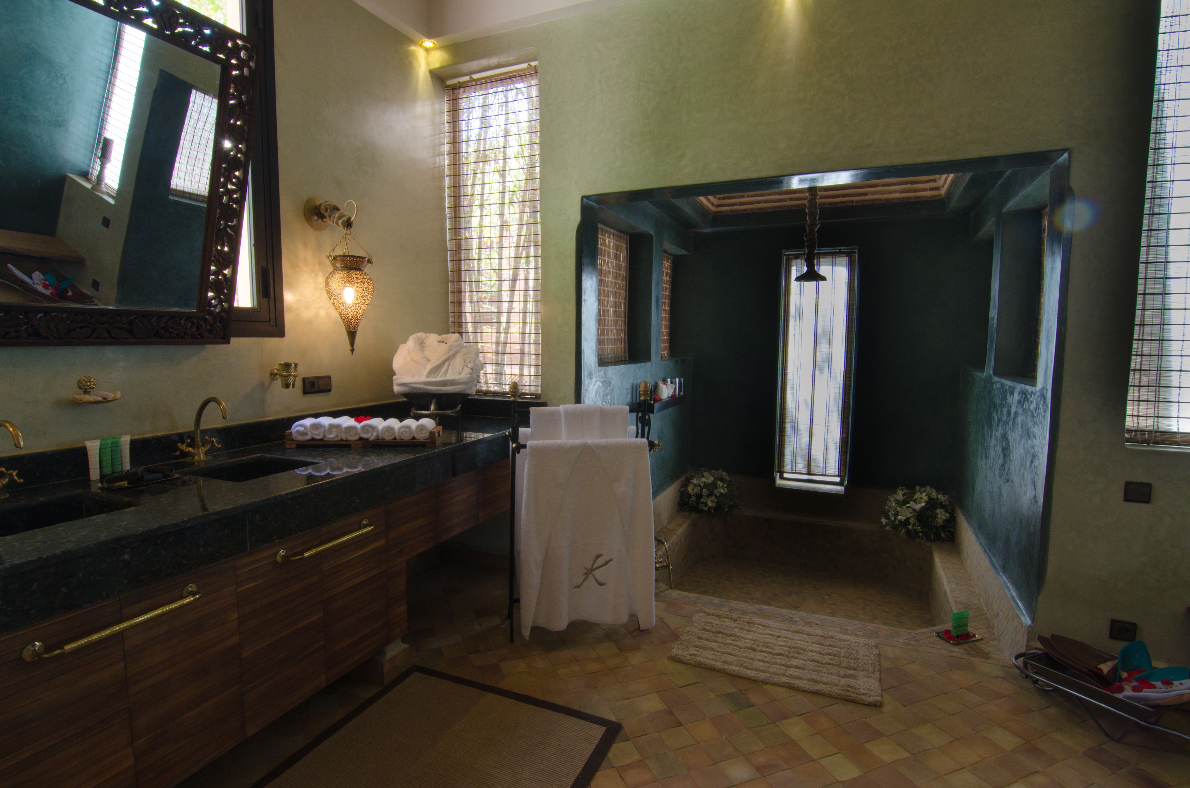Un bagno con uno specchio grande, un lavandino con piano d'appoggio scuro e un porta asciugamani.