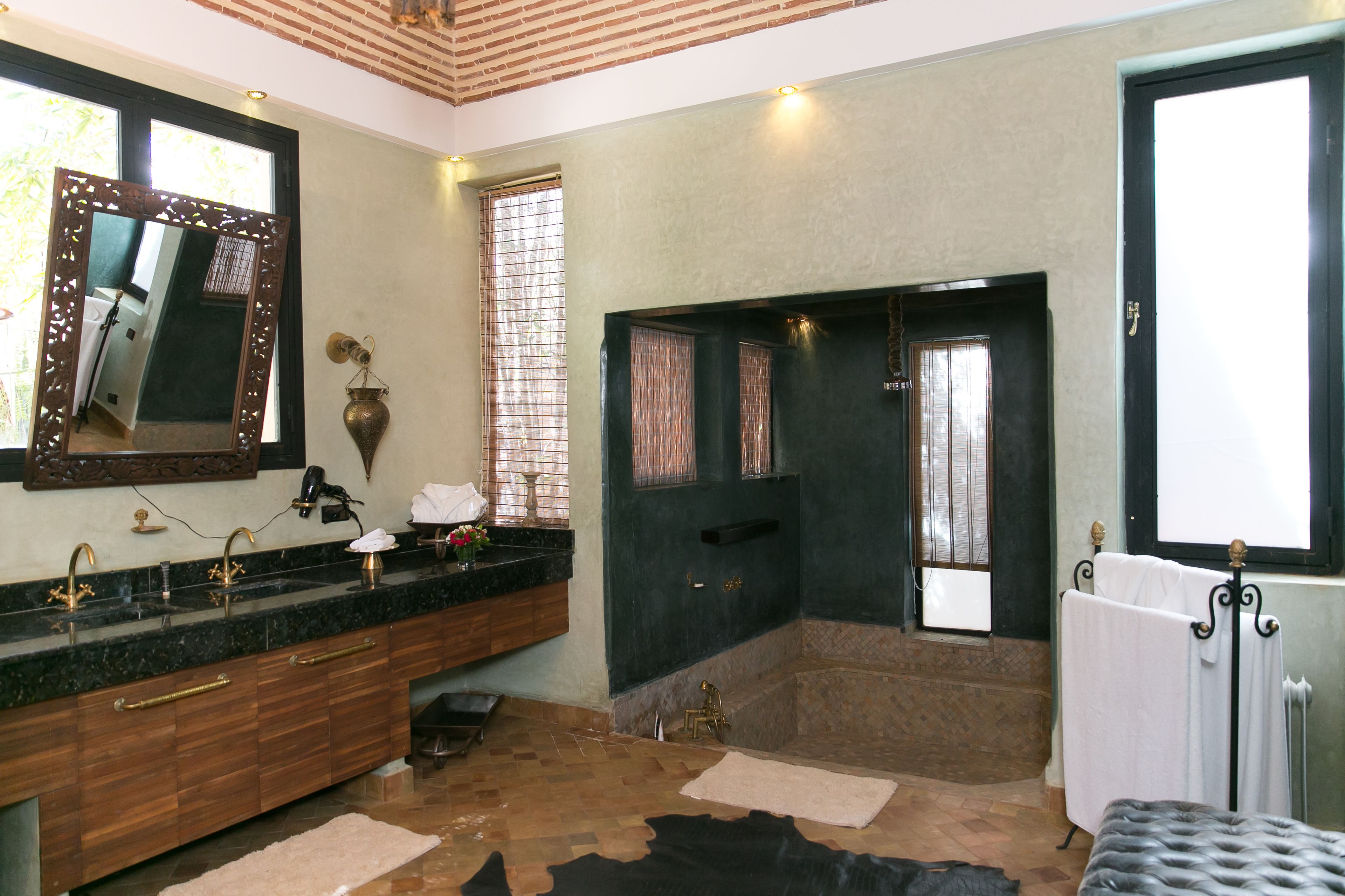 A bathroom with a large mirror, a sink with gold fixtures, a bathtub, and a radiator.