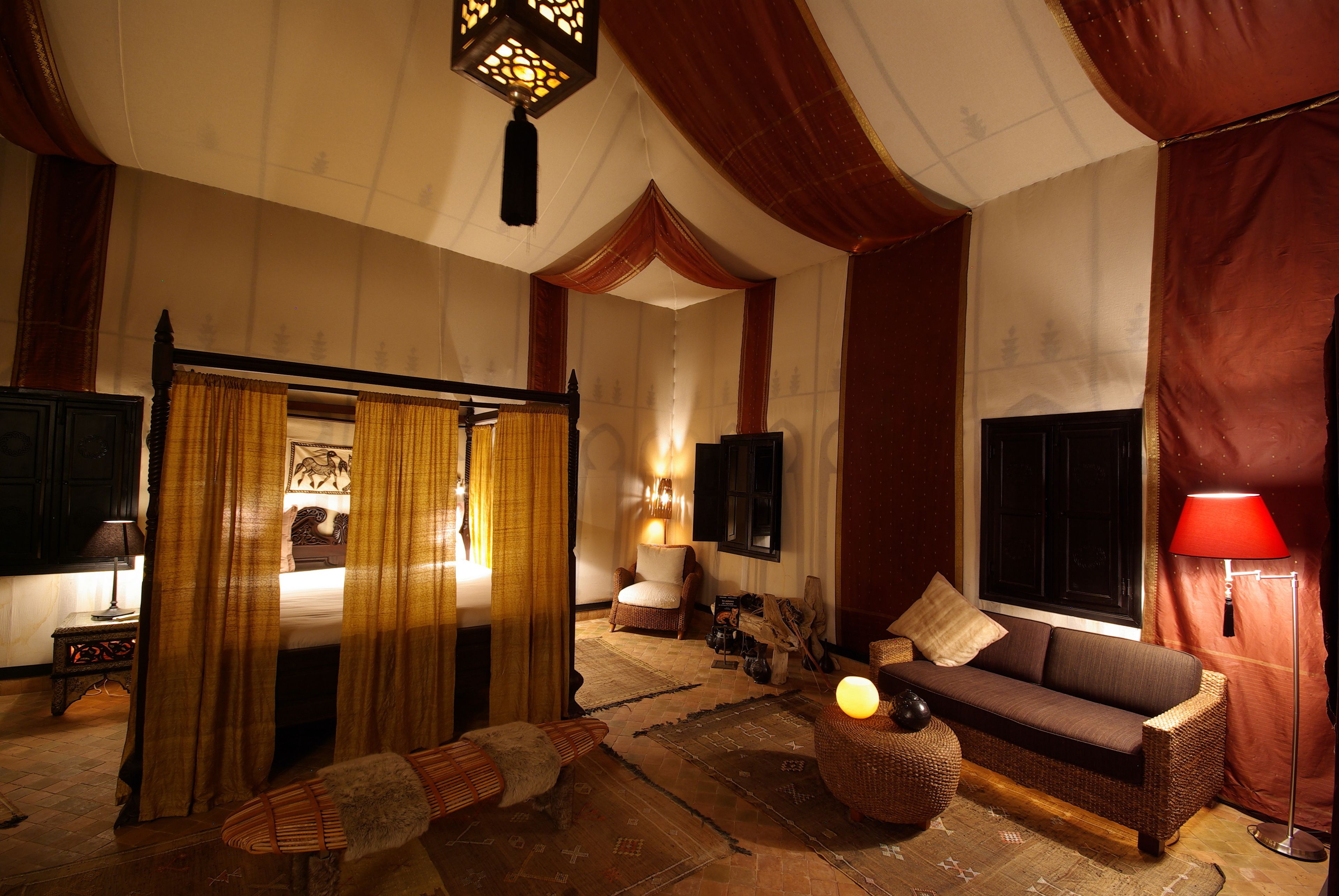 A traditional room with a bed, a sofa, a lamp, and a television.