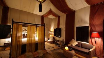 A traditional room with a bed, a sofa, a lamp, and a television.