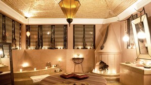 A luxurious bedroom with a large bed, a sitting area, a bathtub, and a vanity with a mirror. - Lodge K Hôtel & Spa (Marrakech)