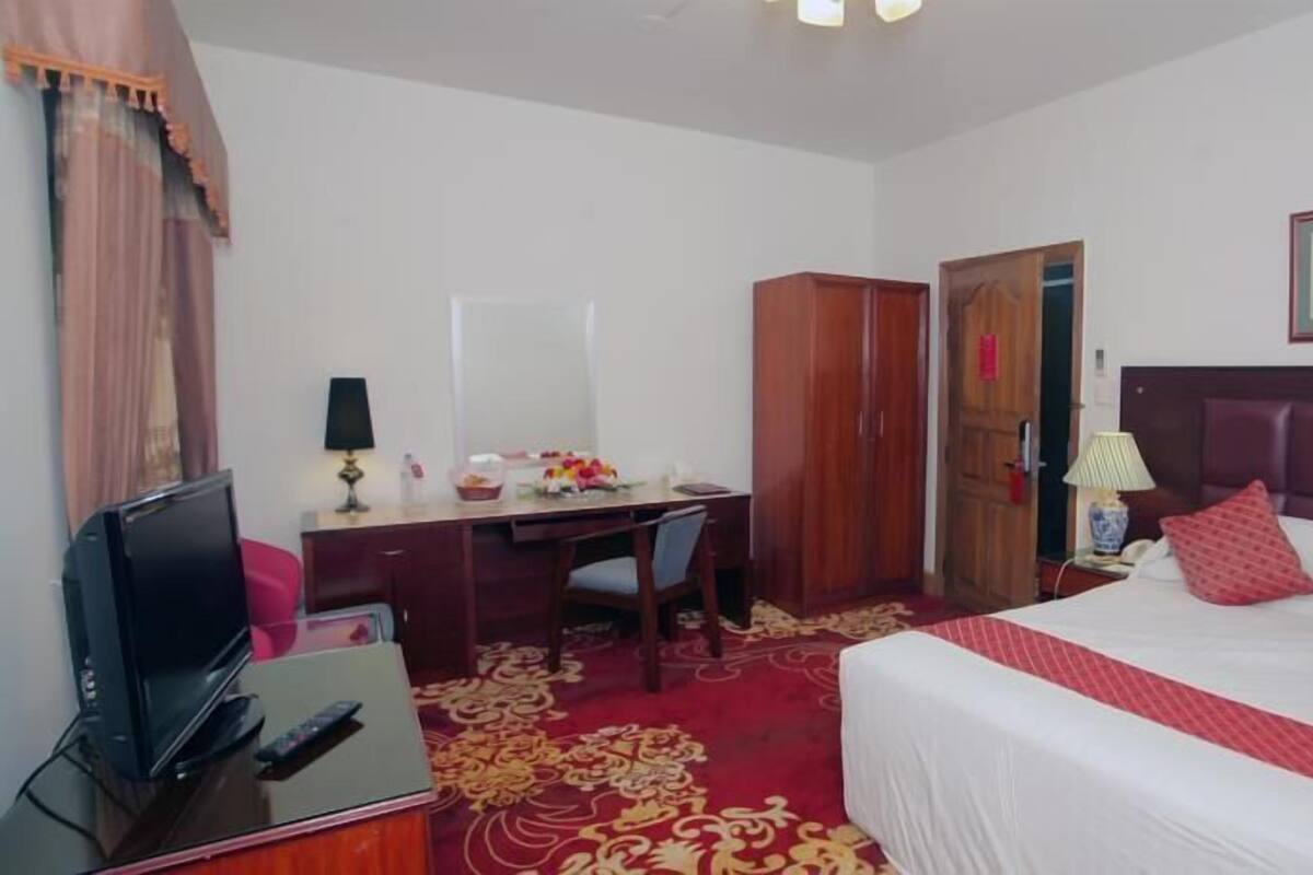Une chambre d’hôtel équipée d’un lit, d’un bureau, d’une télévision et d’une armoire.