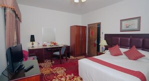 A hotel room with a bed, a desk, a television, and a wardrobe. - Rigs Inn (Dhaka)