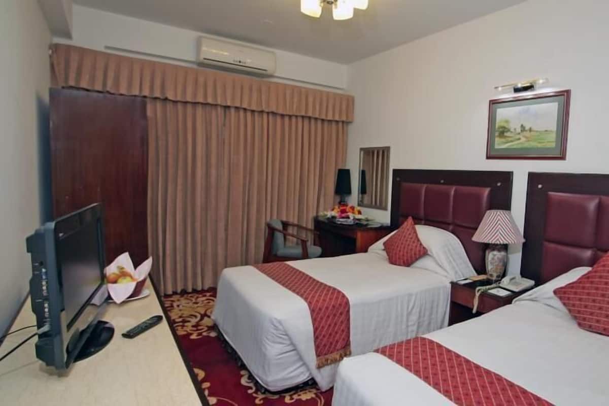 Une chambre d’hôtel avec deux lits, un bureau, une chaise, une télévision et un appareil de climatisation.