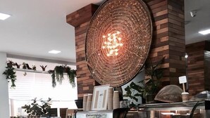 Een café met een telwerkblad van hexagontegels, een koffieapparaat en een vitrine met gebak.