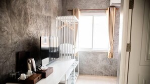 Een moderne kamer met een wit bureau, een televisie, een radiator en een raam met gordijnen.