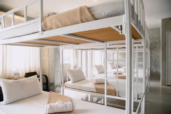Dormitorio con literas, ropa de cama blanca y cabecero de madera.