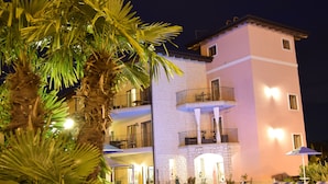 A multi-story building with a pool area, outdoor seating, and palm trees.