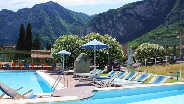 A pool area with lounge chairs and umbrellas, surrounded by mountains.