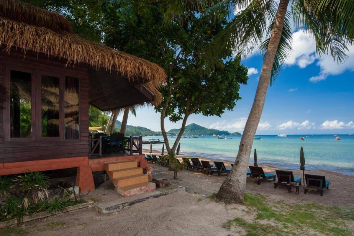 Eine Strandhütte mit einem Reetdach, einer Holzterrasse und Blick auf den Ozean.