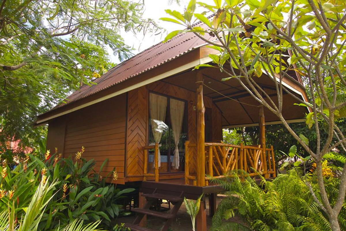Eine Holzhütte mit Veranda, umgeben von üppigem Grün.