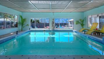 Alberca techada, alberca al aire libre y camastros