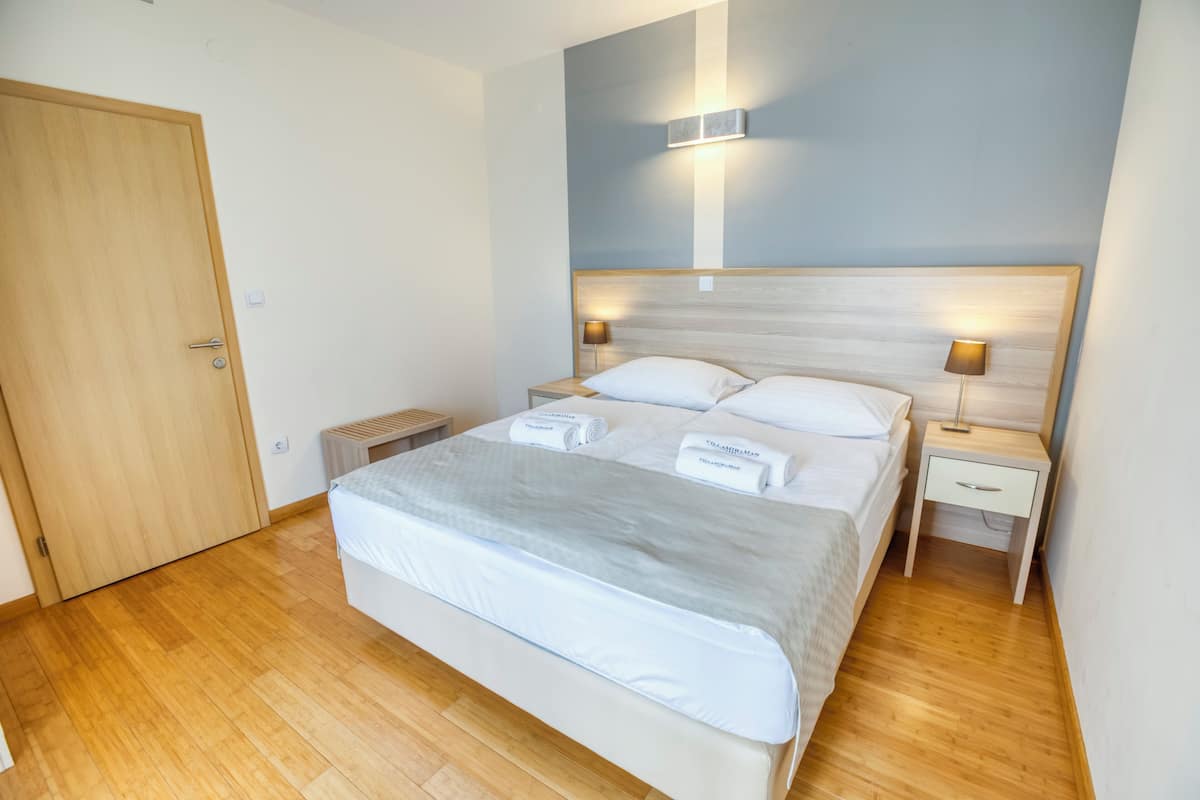 A neatly arranged bedroom with a large bed, two bedside tables, and a wooden door.