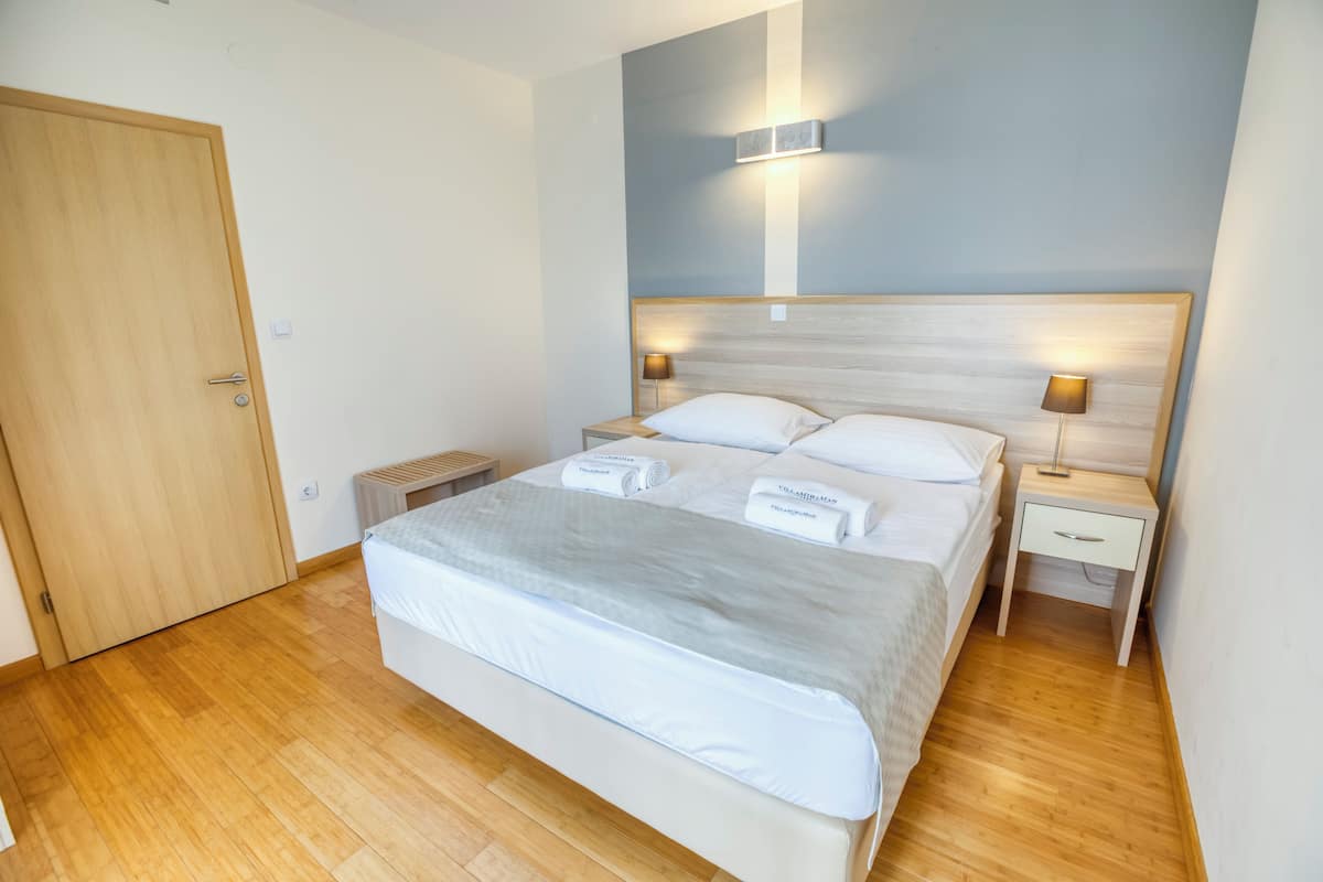 A neatly arranged bedroom with a large bed, two bedside tables, and a wooden door.