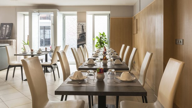 A dining area with a long table set for a meal, surrounded by chairs. - Hotel Eiffel XV (Paris)
