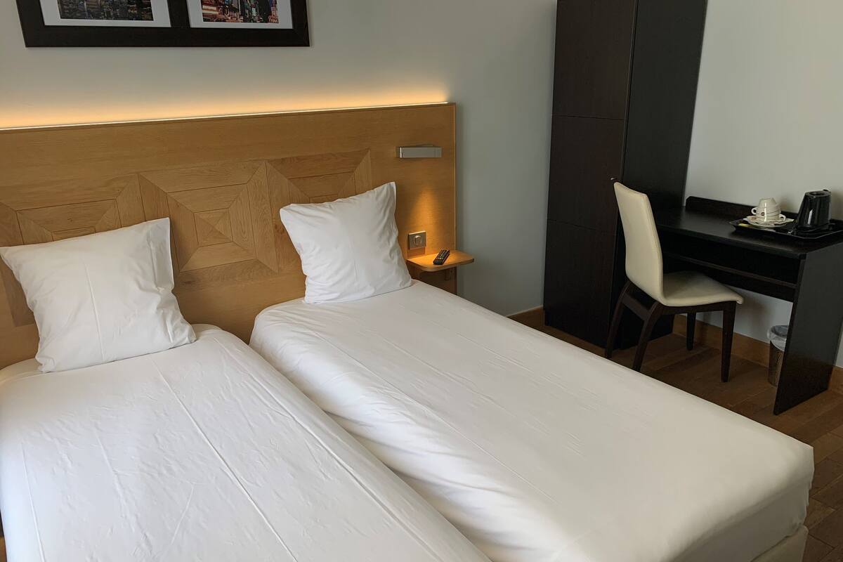 A hotel room with two beds, a desk, and a chair.