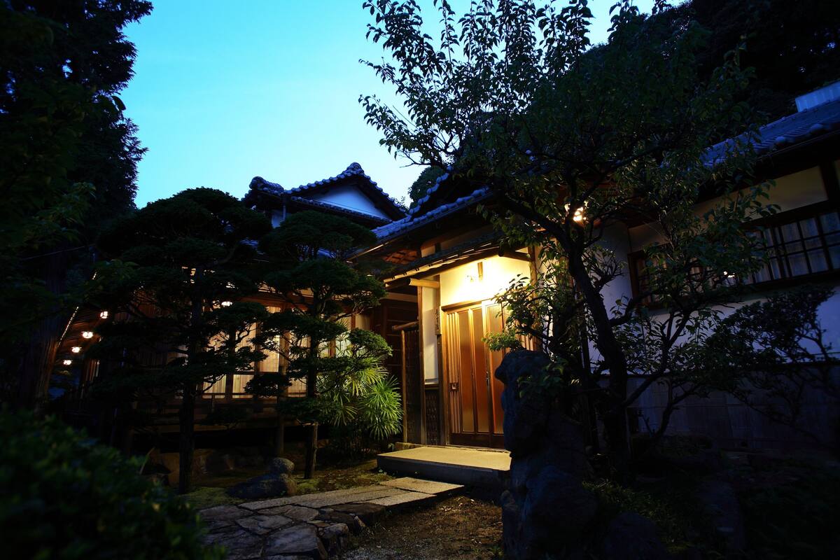 Een traditioneel Japans gebouw met een houten gevel en een pad van stenen dat naar de ingang leidt.