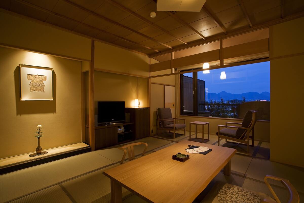 Een traditionele Japanse kamer met tatami vloerbedekking, een lage houten tafel en een televisie.