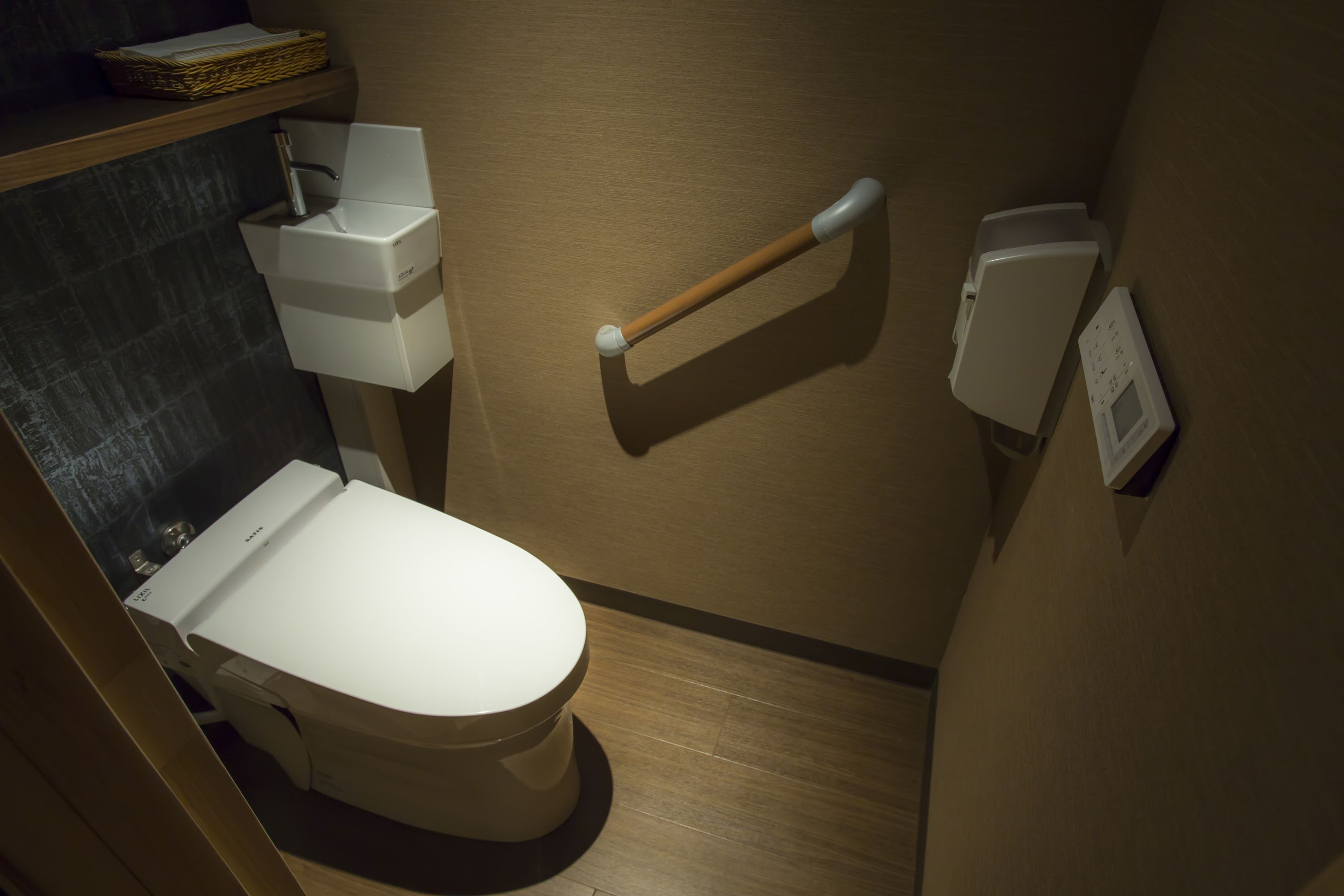 Ein modernes Badezimmer mit Toilette, einem Händetrockner und einem Papierhandtuchspender.
