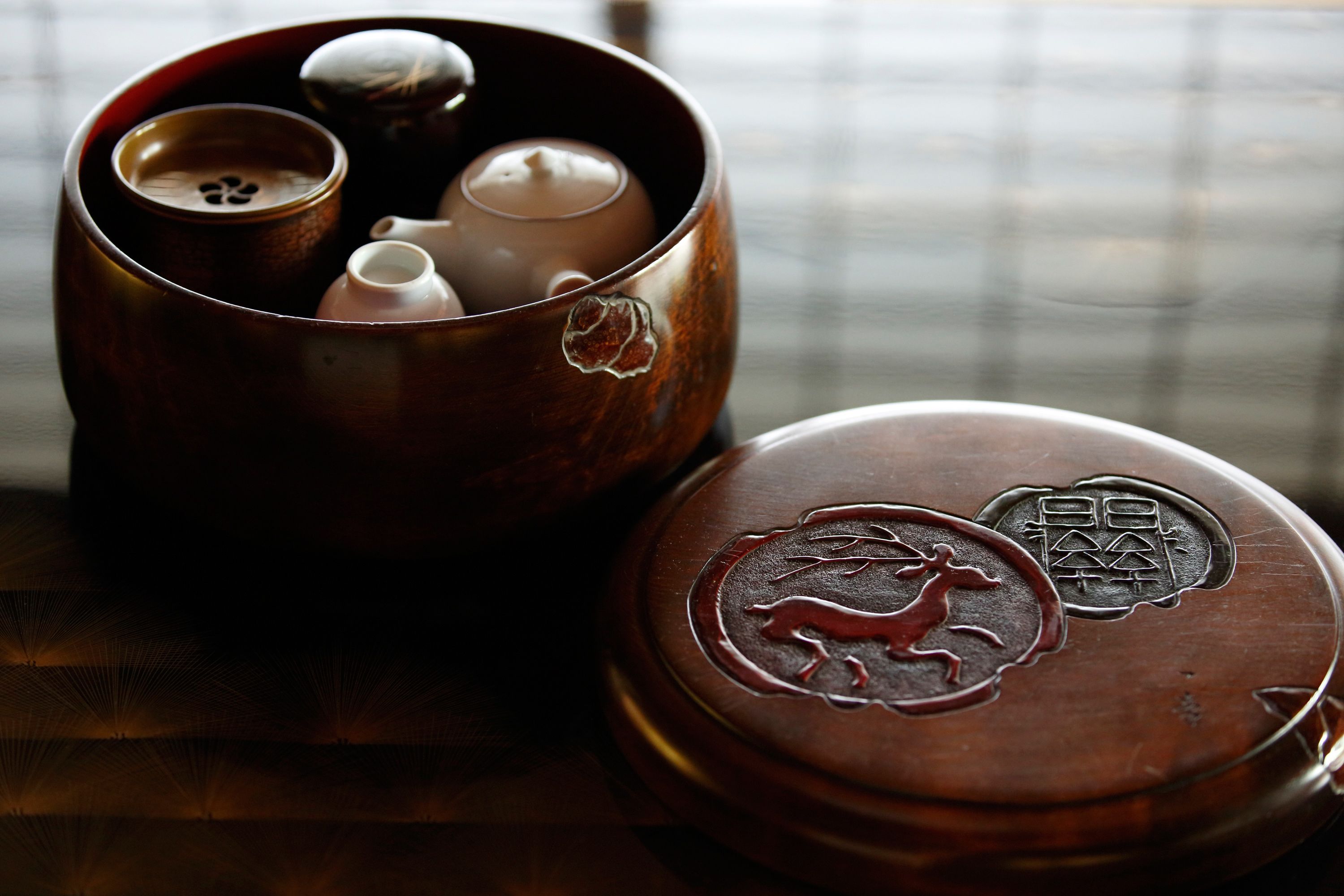 A traditional tea set with a wooden lid featuring a lion design and Chinese characters.