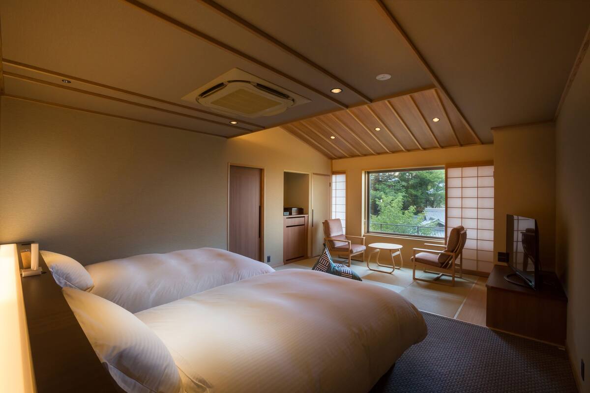 Een ruime slaapkamer met een groot bed, een televisie en uitzicht op de omgeving door een groot raam.