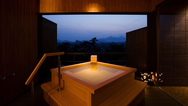 Un interior moderno con un mostrador de recepción de madera y vistas a un paisaje urbano al anochecer.