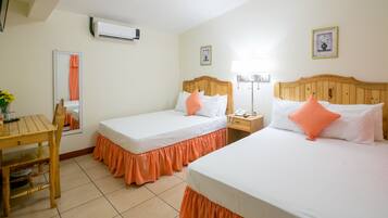 Quarto de hotel com duas camas, uma mesa de madeira, um espelho e uma mesinha de cabeceira.