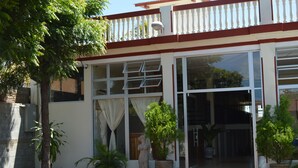 A building with large glass doors, a balcony with a railing, and potted plants. - Hotel la Estación Granada (Granada)