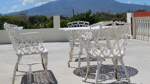 A rooftop terrace with white metal chairs and tables, a view of a mountain, and a clear blue sky. - Hotel la Estación Granada (Granada)