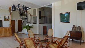 A spacious living area with a wooden staircase, wicker chairs, a potted plant, and a flat-screen TV mounted on the wall. - Hotel la Estación Granada (Granada)