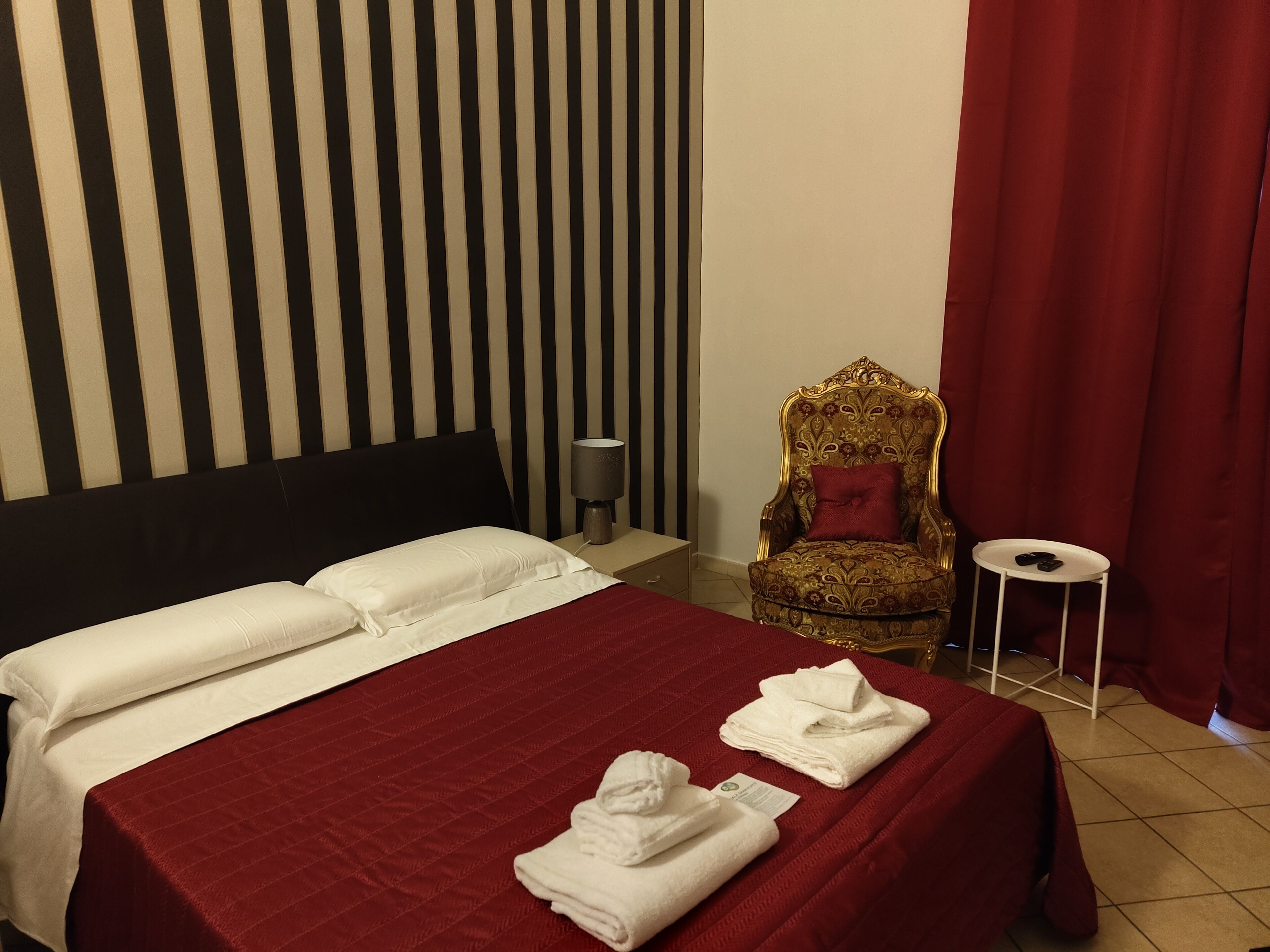 Una habitación de hotel con una cama, una silla, una mesita y una cortina.