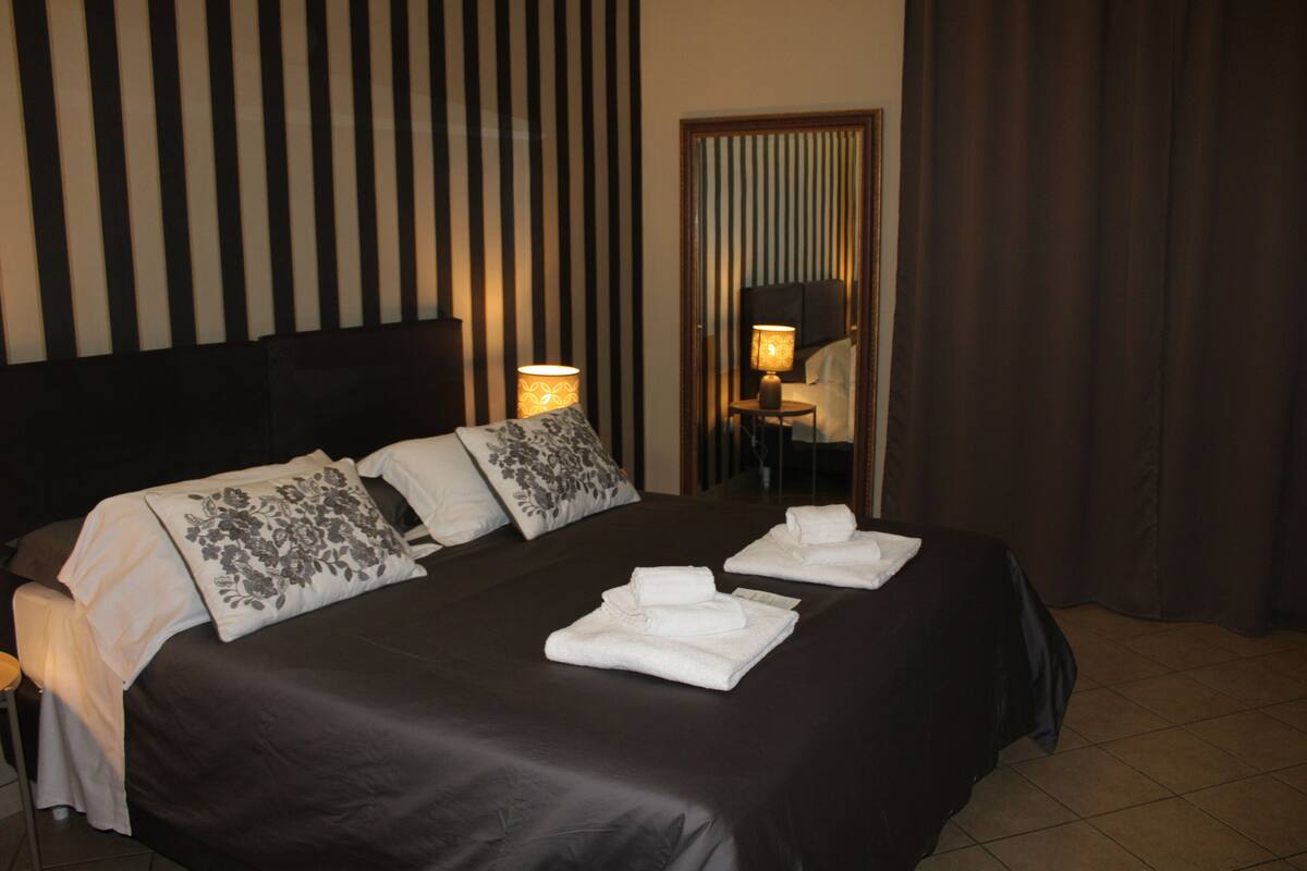 A hotel room with a large bed, two bedside lamps, and a mirror on the wall.