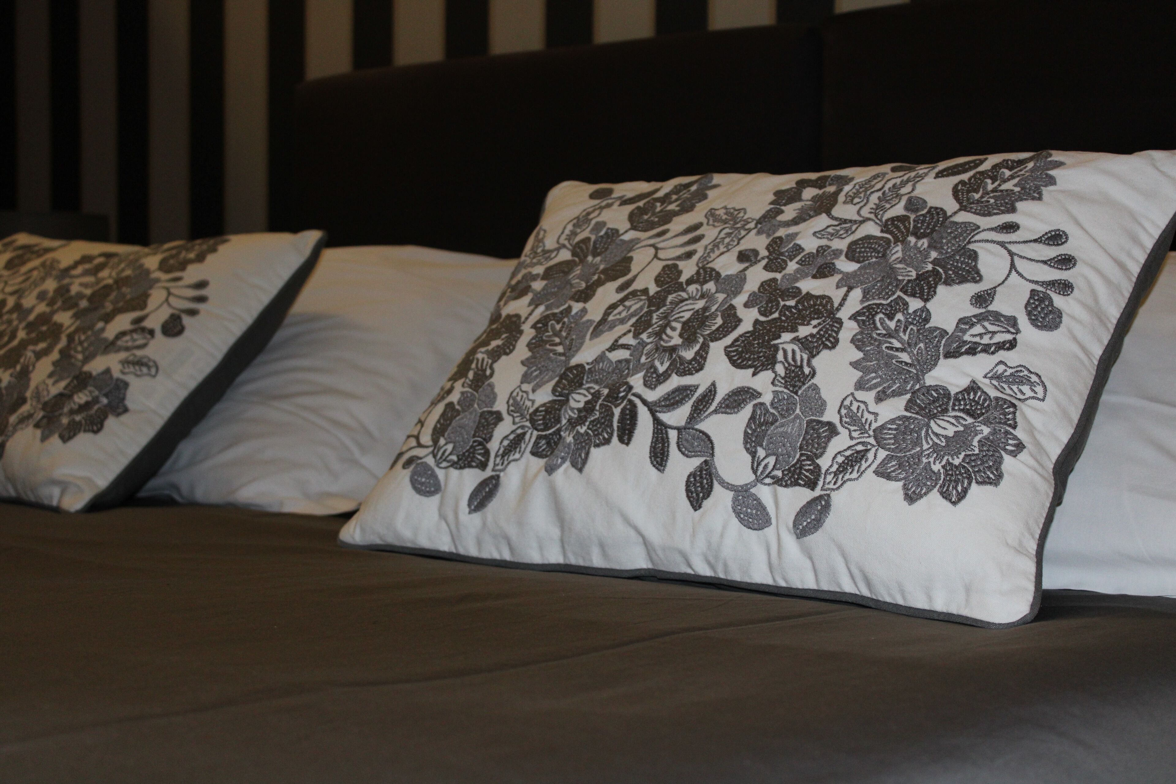 A bed with two pillows featuring a floral pattern.